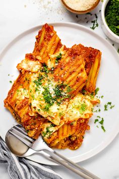 a white plate topped with lasagna covered in sauce and parmesan cheese