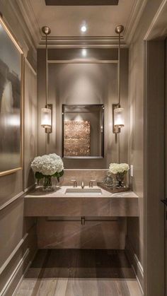 a bathroom with two sinks, mirrors and flowers on the counter in front of it