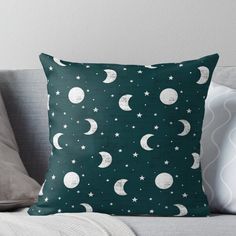 a green pillow with white stars and the moon in the night sky on a couch