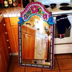 a mirror that is sitting on the floor in front of a stove top oven and cabinets