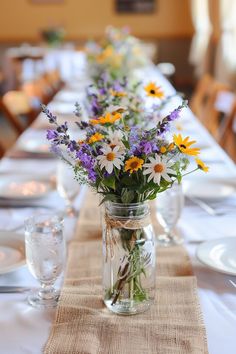 the table is set with flowers in mason jars