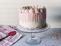 a white cake with sprinkles and icing on a plate next to a fork