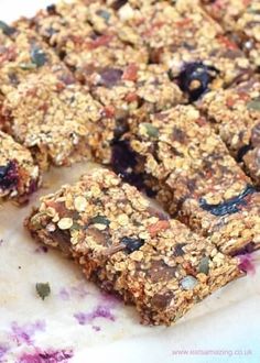 granola bars cut into squares on top of a white plate with blueberries and other toppings