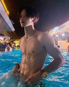 a shirtless man standing in the middle of a swimming pool with his hand on his hip