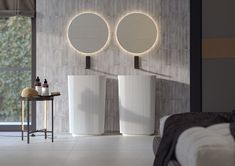 two round mirrors are on the wall above three white vases and a table in front of it