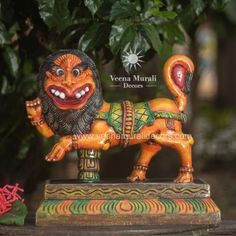 a lion statue sitting on top of a wooden table next to a potted plant