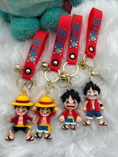 three keychains with cartoon characters on them sitting next to a stuffed animal bear