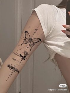 a woman is taking a selfie with her cell phone and butterfly tattoo on her arm