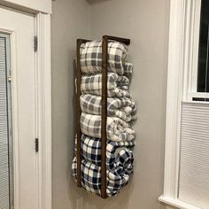 a stack of blankets hanging on the wall in a bathroom next to a door and window