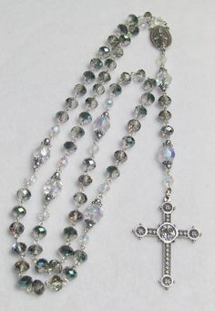 "This rosary is made with iridescent green glass beads, clear faceted glass beads, silver seed beads, silver accents, silver medal and silver cross What does the rosary symbolize? The rosary is more than a prayer. It symbolizes our destiny in and with God according to Mary's example. To live up to this destiny, we need faith in God's marvelous deeds for us, perseverance in his ways (hope) and a practical attitude toward living our faith, that is charity.  The word rosary itself comes from the La Silver Faceted Beads Rosary Cross, Silver Rosary With Miraculous Medal And Round Beads, Spiritual Cross Rosary With Faceted Beads, Silver Beaded Rosary With Spiritual Style, Silver Rosary With Faceted Beads, Silver Beaded Spiritual Rosary, Silver Rosary With Faceted Beads For Gift, Silver Rosary With Faceted Round Beads, Silver Rosary With Faceted Beads As Gift