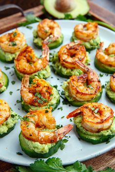 shrimp and avocado stuffed cucumbers on a white plate with garnish