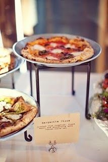 several different types of pizzas on display at a wedding or reception table with place cards