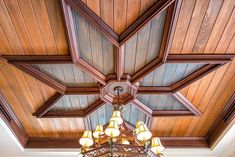 a chandelier hanging from the ceiling in a room with wood paneled ceilings