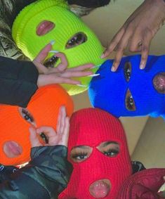 four people wearing knitted masks with fingers in the middle