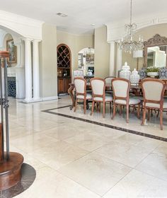 a formal dining room with marble flooring and chandelier