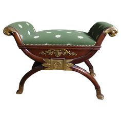 an ornate wooden bench with green and white fabric on the seat, against a white background