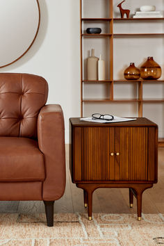 a brown leather chair sitting next to a wooden cabinet