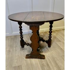 an old wooden table sitting on top of a hard wood floor next to a white wall