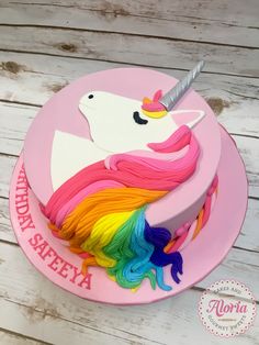 a pink cake with a rainbow unicorn on it