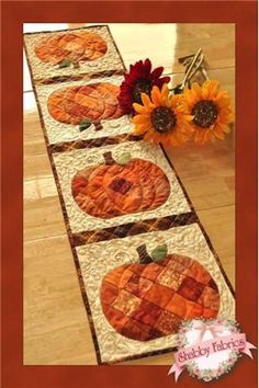 the table runner has four pumpkins on it and two sunflowers next to it