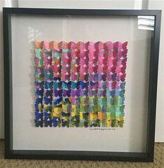 an art work made out of colored tissue paper in a black frame on the floor