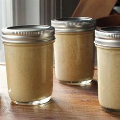 three jars filled with food sitting on top of a wooden table