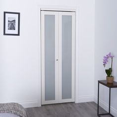 a bedroom with white walls and wooden floors