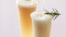 two tall glasses filled with liquid and topped with a sprig of fresh rosemary