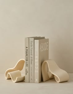 two bookends sitting next to each other in front of a white wall with books on it