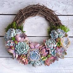 a wreath made out of succulents on top of a white wooden surface