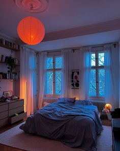 a bed room with a neatly made bed next to two windows and a book shelf