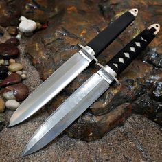 two knives sitting on top of rocks next to each other