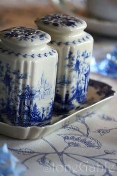 two blue and white jars sitting on top of a tray