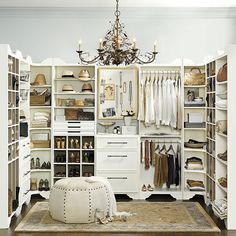 an open closet with clothes and shoes on shelves, chandelier hanging from the ceiling