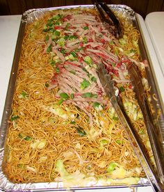 a tray filled with noodles, meat and veggies on top of a table