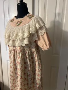 This is a gorgeous vintage Victorian/English farm style dress. Reminds me of Little House on the Prairie!  This dress is quite small and fit on a small size 1-3 mannequin Armpit to armpit 21" Collar 9" across  Top of shoulder to sleeve end 13" Sleeve diameter 12"  Length approx 44" It is in perfect condition Vintage Long Sleeve Floral Embroidery Dress, Vintage Long Sleeve Dress With Floral Embroidery, Spring Prairie Dress With Lace Trim, Cottagecore Dresses With Lace Trim, Spring Pastoral Prairie Dress With Lace Trim, Cream Prairie Dress With Ruffles In Cottagecore Style, Cottagecore Cream Vintage Dress With Ruffles, Cream Cottagecore Prairie Dress With Ruffles, Vintage Victorian Dress With Short Sleeves For Spring