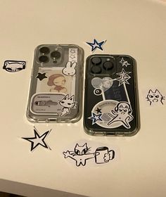 two cell phones sitting next to each other on top of a white table with stickers