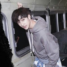 a young man standing on the inside of a train looking at the camera while wearing a hoodie