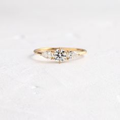 three stone engagement ring in yellow gold and white diamonds on a plain surface with snow flakes