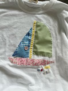 a white shirt with a sailboat applique on it