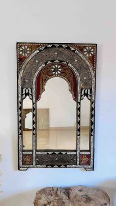 a mirror hanging on the wall next to a table with a tree stump in front of it