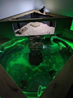 an aquarium with green lights and rocks in the water