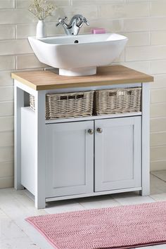 a white sink sitting on top of a wooden counter next to a pink area rug