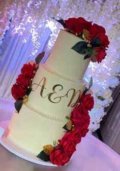 a three tiered wedding cake with red flowers on top and monogrammed initials