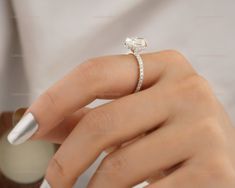 a woman's hand with a diamond ring on her finger and white nail polish