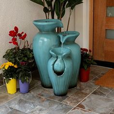 two blue vases sitting next to each other on a tile floor with potted plants