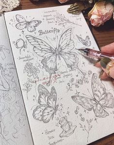 a person holding a pen and drawing butterflies on paper