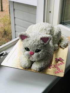 a white teddy bear sitting on top of a table next to a window sill