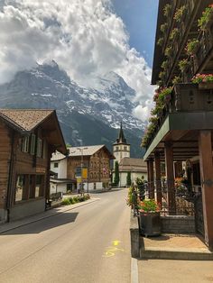 a street lined with wooden buildings and tall mountains in the backgrouds behind them