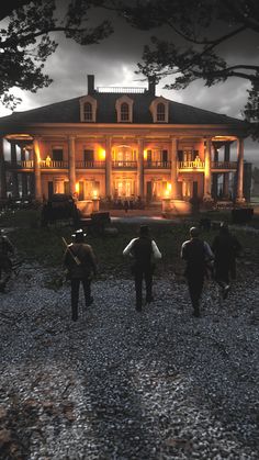 four people walking towards a large house at night